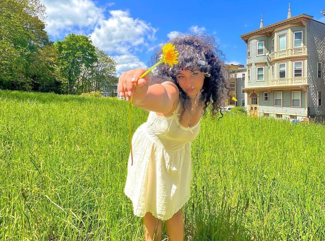 girl with black curls with flower