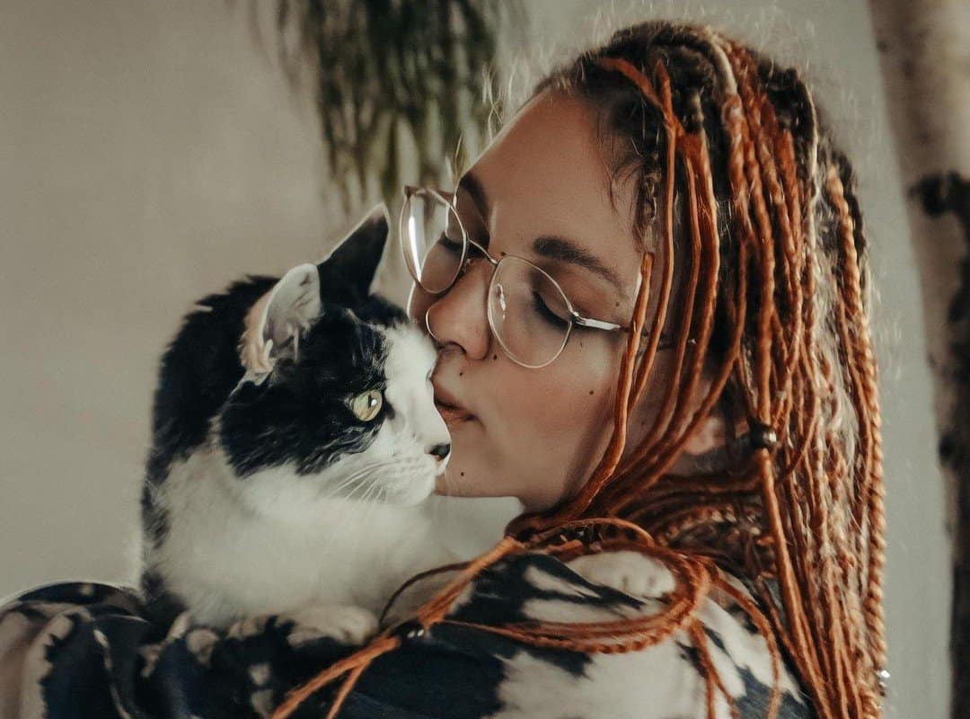 girl with hippie dreads hugs cat