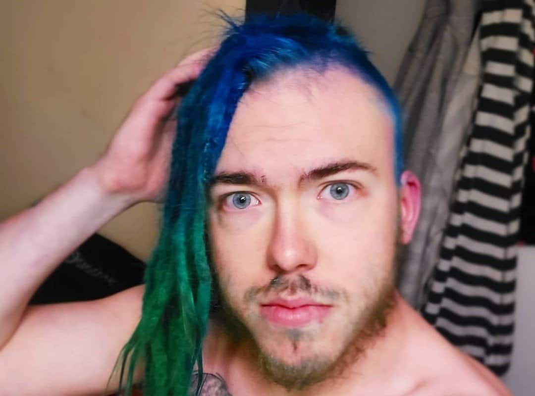 man with dark blue and green ombre dyed dreads