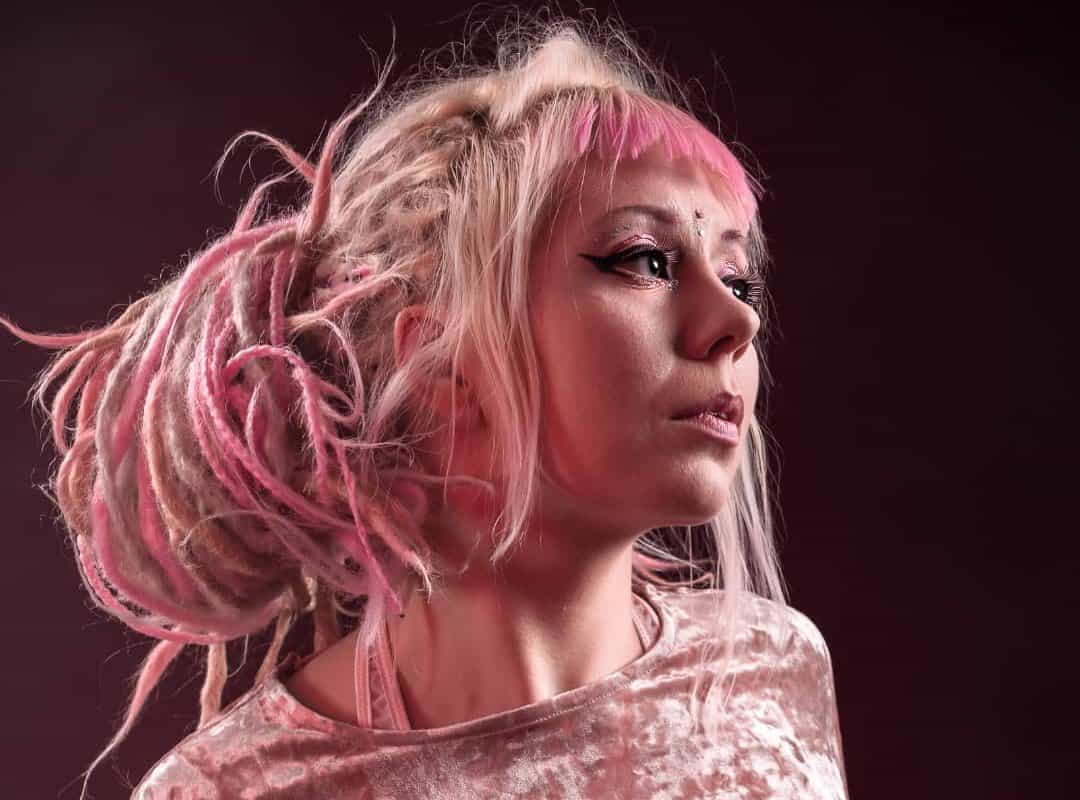 girl with pink and white ombre dyed dreads in messy bun
